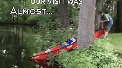 A Man Is Pulling A Kayak Out Of The Water . GIF