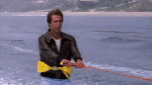 A Man Is Pulling A Rope In The Water With A Yellow Belt That Says T On It GIF
