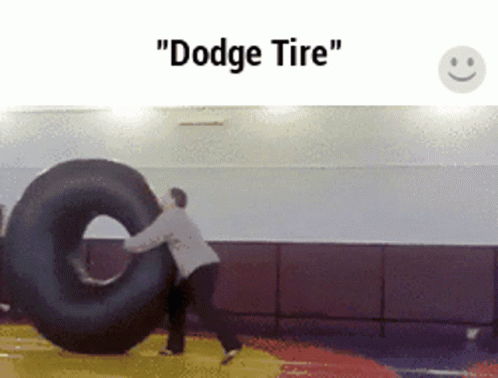 A Man Is Pushing A Tire That Says " Dodge Tire " On It GIF
