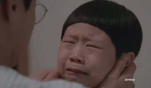 A Man Is Putting His Hand On A Child 'S Face Who Is Crying . GIF