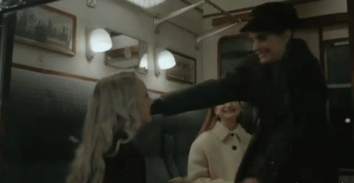 a man is putting his hand on a woman 's head in a train car .