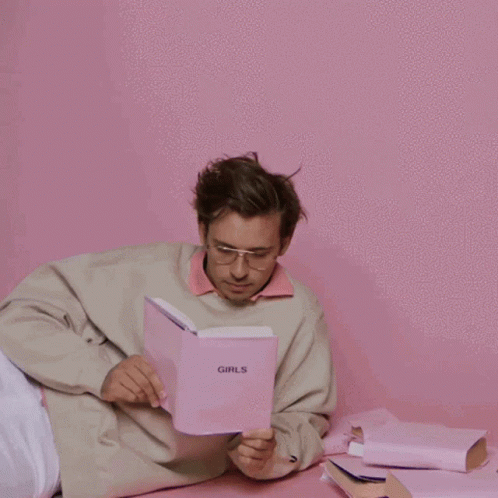 A Man Is Reading A Book Called Girls GIF