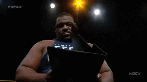 A Man Is Reading A Book In A Dark Room With A Lot Of Lights Behind Him . GIF