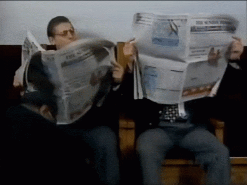 A Man Is Reading A Newspaper That Says The New York Times GIF
