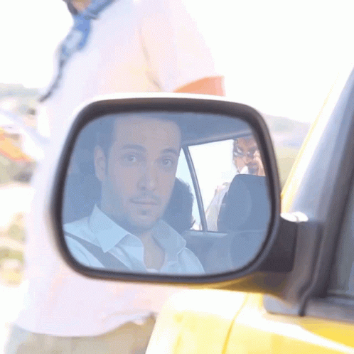 A Man Is Reflected In The Side Mirror Of A Yellow Car GIF