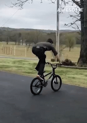 A Man Is Riding A Bike Down A Road And The Words Awesome Are On The Bottom Right GIF