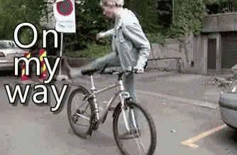 A Man Is Riding A Bike In A Parking Lot With The Words On My Way Behind Him GIF