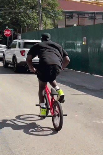 A Man Is Riding A Bike In Front Of A Red Stop Sign GIF