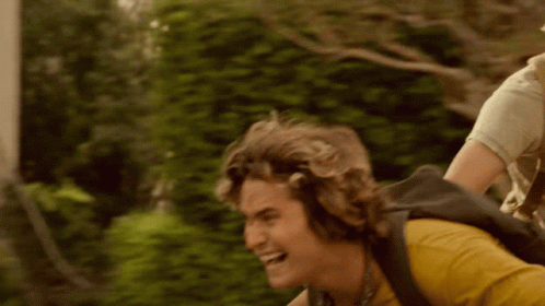 A Man Is Riding A Bike With A Backpack On His Back . GIF