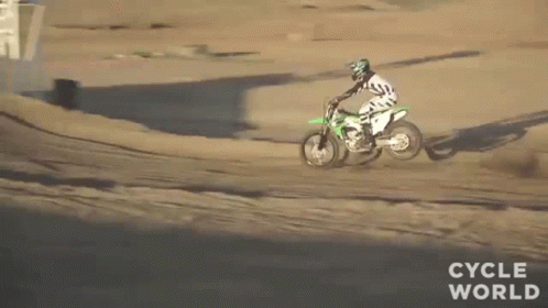 A Man Is Riding A Dirt Bike Down A Dirt Track . GIF