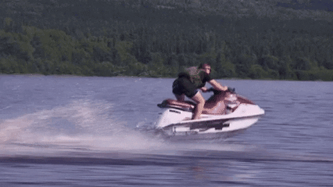 A Man Is Riding A Jet Ski In A Lake GIF