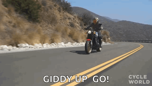 A Man Is Riding A Motorcycle Down A Road With The Words Giddy Up Go Behind Him . GIF