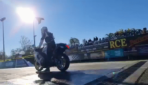 A Man Is Riding A Motorcycle In Front Of A Fence With Rce Written On It GIF
