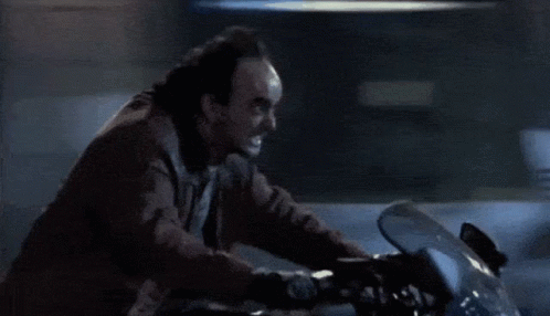 A Man Is Riding A Motorcycle On A Dark Street GIF