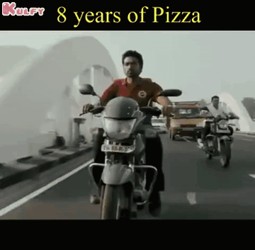 A Man Is Riding A Motorcycle On A Highway With The Words 8 Years Of Pizza Above Him GIF
