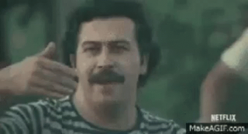 A Man Is Riding A Motorcycle With A Group Of People Behind Him And A Sign That Says `` Venga '' . GIF