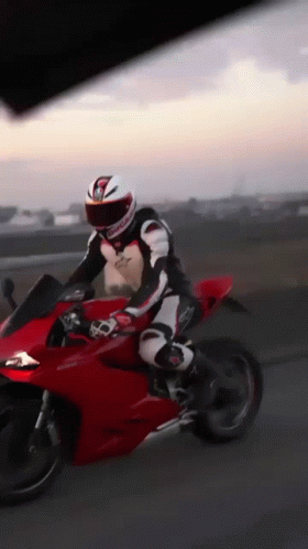 A Man Is Riding A Red Motorcycle With A Helmet That Has The Letter G On It GIF