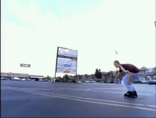 a man is riding a roller skate in a parking lot while holding a sign .
