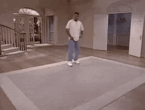 A Man Is Riding A Skateboard On A Rug In A Room . GIF