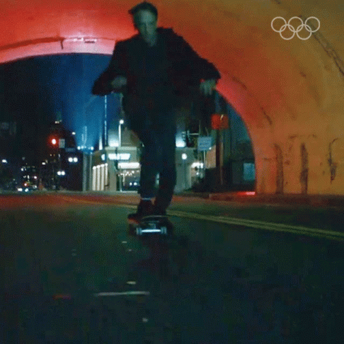 A Man Is Riding A Skateboard Through A Tunnel With The Olympic Rings On The Bottom GIF