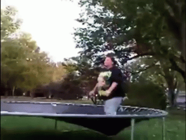 A Man Is Riding A Trampoline With A Dog In His Arms GIF