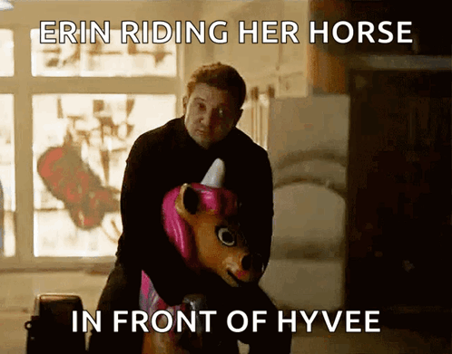 A Man Is Riding A Unicorn In Front Of A Sign That Says " Erin Riding Her Horse In Front Of Hyvee " GIF