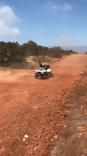 a man is riding a white atv on a dirt road