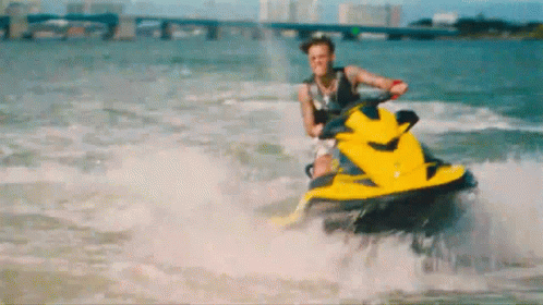 A Man Is Riding A Yellow Jet Ski On The Water GIF