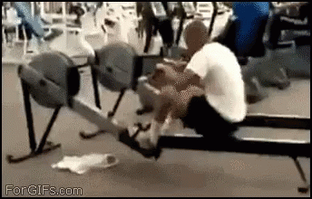 A Man Is Rowing A Rowing Machine In A Gym GIF