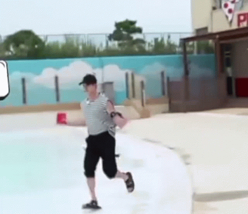 A Man Is Running Across A Swimming Pool While Holding A Red Cup . GIF