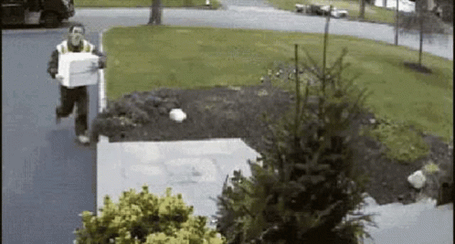 A Man Is Running Down The Street Carrying A Box In His Hand . GIF