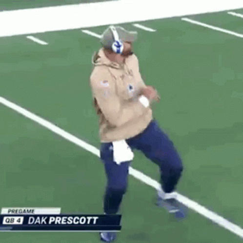 A Man Is Running On A Football Field Wearing Headphones And A Hat . GIF