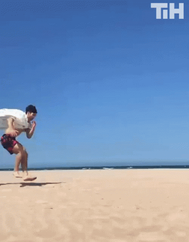 A Man Is Running On A Sandy Beach With The Letters Th Above Him GIF