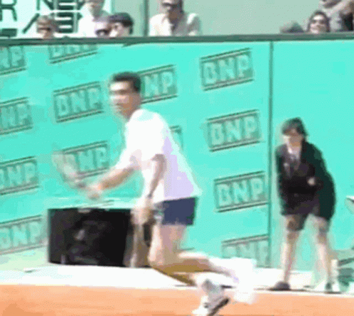 A Man Is Running On A Tennis Court In Front Of A Wall That Says Bnp GIF