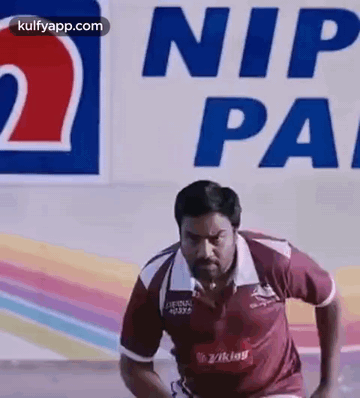 A Man Is Running On A Track In Front Of A Sign That Says Nip Pa . GIF