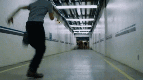 A Man Is Running Through A Tunnel With A Yellow Line On The Floor GIF