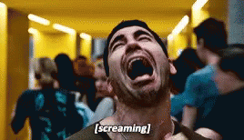 A Man Is Screaming In A Hallway With His Mouth Open . GIF