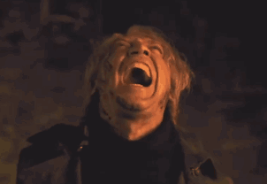 A Man Is Screaming In The Dark With His Mouth Open GIF