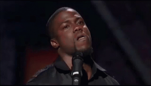 A Man Is Singing Into A Microphone And Making A Face . GIF