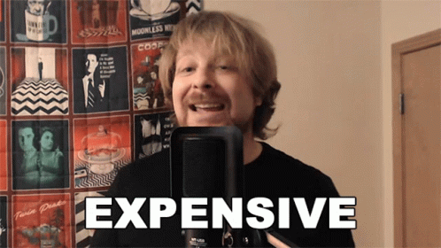 A Man Is Singing Into A Microphone And The Word Expensive Is On The Screen Behind Him GIF