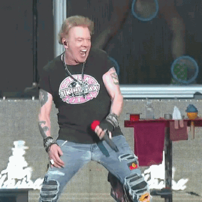 A Man Is Singing Into A Microphone And Wearing A Shirt That Says Skinny Lax GIF