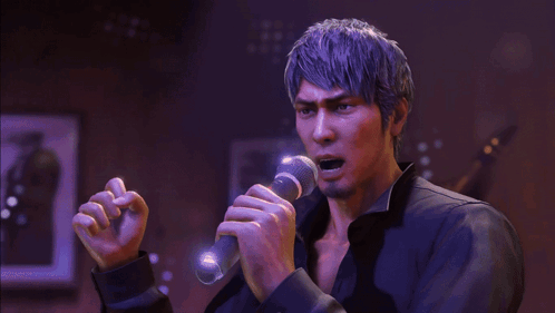 a man is singing into a microphone in a dark room