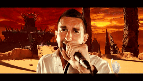 A Man Is Singing Into A Microphone In Front Of A Castle GIF