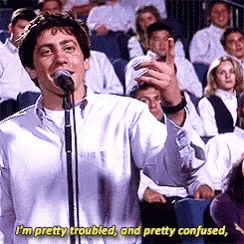 A Man Is Singing Into A Microphone In Front Of A Crowd And Says I 'M Pretty Troubled GIF