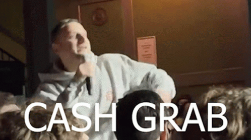 A Man Is Singing Into A Microphone In Front Of A Crowd With The Words Cash Grab Below Him GIF