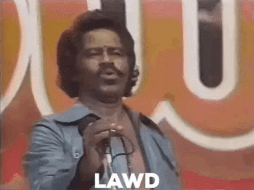 A Man Is Singing Into A Microphone In Front Of A Large Sign . GIF