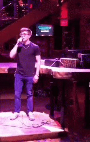 a man is singing into a microphone in front of a sign that says no smoking served