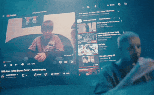 A Man Is Singing Into A Microphone In Front Of A Youtube Screen GIF