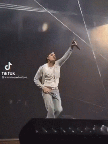 A Man Is Singing Into A Microphone On A Stage With A Tiktok Watermark GIF
