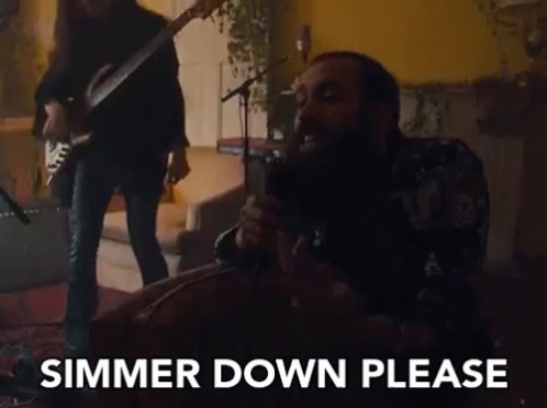 A Man Is Singing Into A Microphone While Another Man Plays A Guitar Behind Him . GIF